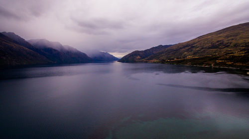 Scenic view of lake by mountains against sky