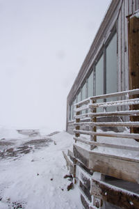 Snow covered staircase by building against sky during winter