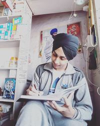 Man in traditional clothing writing on book at store