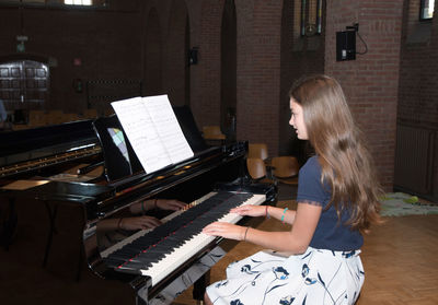 Teenage girl playing the piano in the concert hall, hobby, music