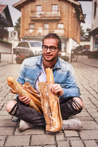 Young man eating bread while sitting on street