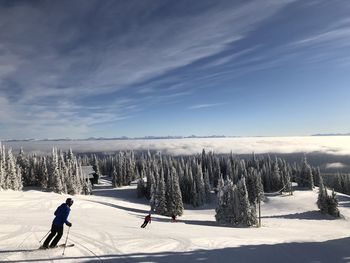 People skiing on field against sky during winter