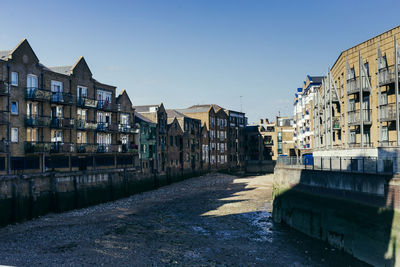 Buildings by canal against sky in city