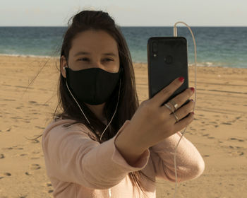 Woman taking selfie with mobile phone at beach