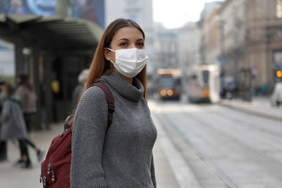 Portrait of young woman wearing mask standing outdoors