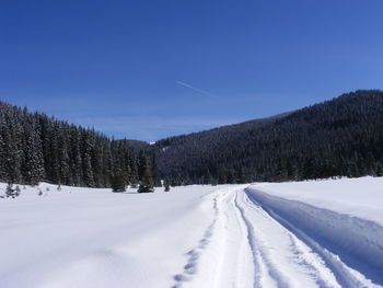 Scenic view of snow covered field against blue sky