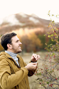 Side view of young man looking away against sky