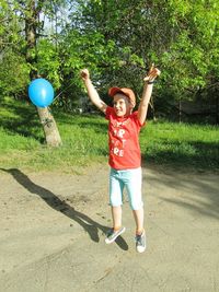 Full length portrait of boy standing by tree