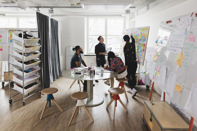 Businesswoman showing colleagues note on whiteboard during meeting in board room