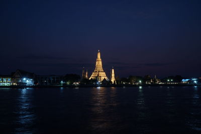 Illuminated building by river at night