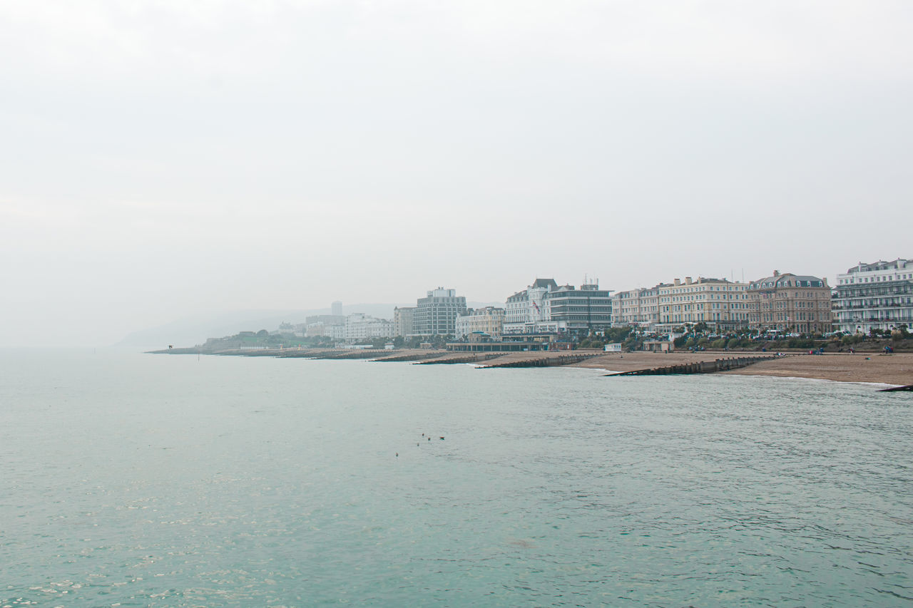 SEA BY BUILDINGS AGAINST SKY