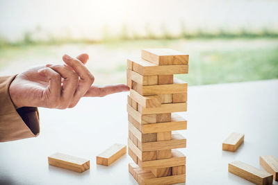 Cropped hand of woman touching stacked dominoes at desk