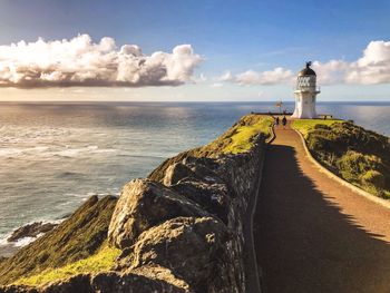 Lighthouse by sea against sky