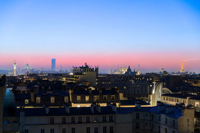 Illuminated cityscape against sky during sunset