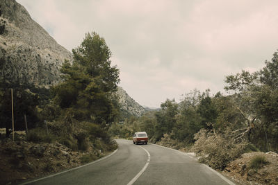 Van moving on road towards mountains against sky