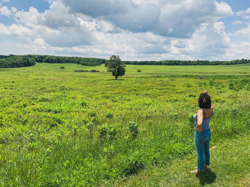 Rear view of a woman standing at edge of a field