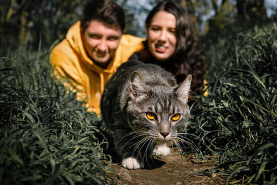 Portrait of man and woman by cat in grass