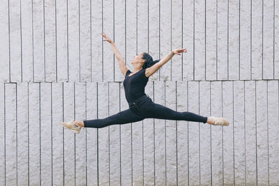 Full length of woman dancing against wall