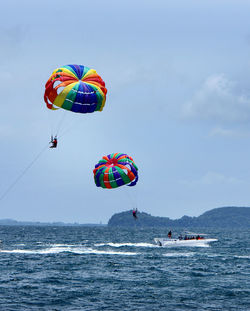 People paragliding over sea against sky