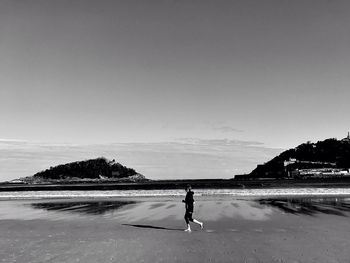 Man walking on beach against sky