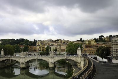 Bridge over river in city against sky