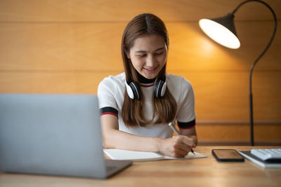 Woman writing in book at home