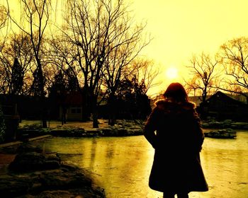 Silhouette of woman standing on tree trunk