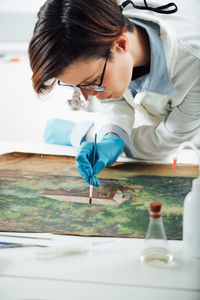 Restoring old oil painting, conservator removing varnish from an oil painting