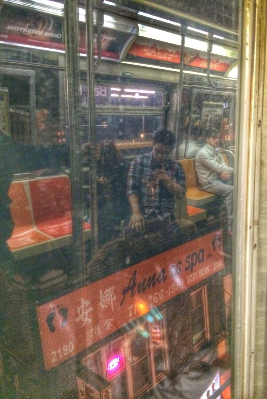 indoors, illuminated, night, glass - material, text, transparent, communication, window, transportation, western script, store, reflection, mode of transport, incidental people, public transportation, railroad station, blurred motion, non-western script, built structure, land vehicle