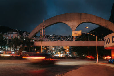 View of bridge over street in city at night
