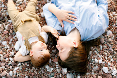 High angle view of mother and daughter lying on pebbles