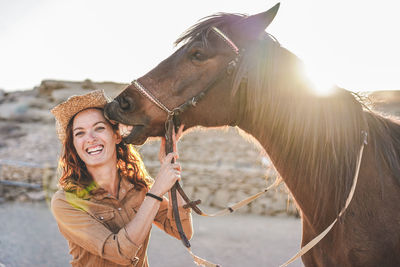 Portrait of smiling woman with horse against sky