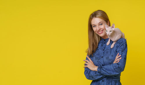 Young woman standing against yellow background