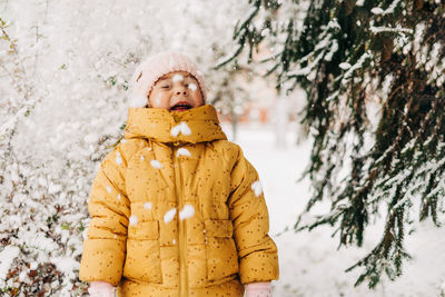 Cute girl standing in snow during winter