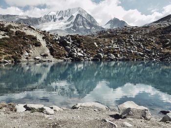 Scenic view of lake by snowcapped mountains against sky