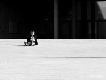 Full length of woman sitting on floor against building