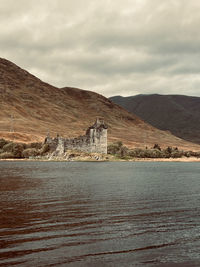 Lake and abandoned architecture against mountains