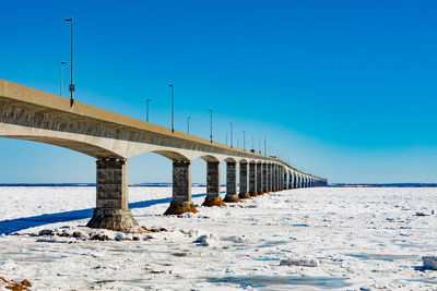 Bridge over calm sea against clear blue sky