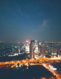 Illuminated cityscape by sea against sky at night