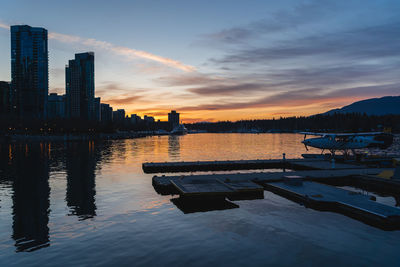 View of lake and buildings against sky during sunset