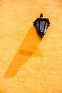 Low angle view of electric lamp on yellow wall