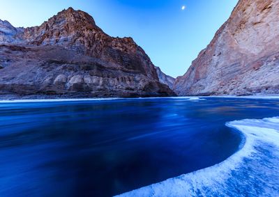 Scenic view of sea and mountains against blue sky