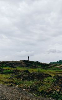 Man standing on green landscape against sky