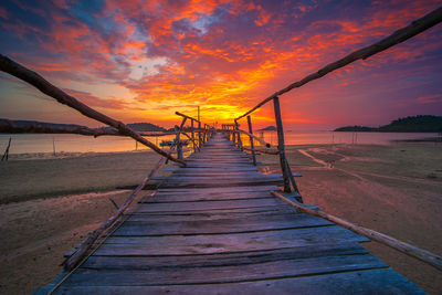 Pier over sea against orange sky