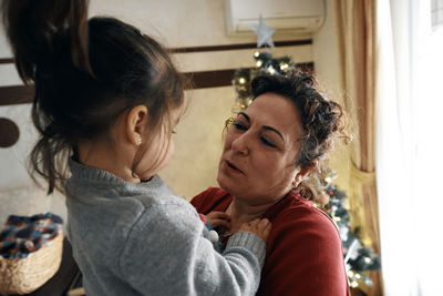 Grandparents decorate the christmas tree with their little granddaughter