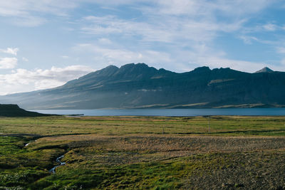Scenic view of river by mountains against sky