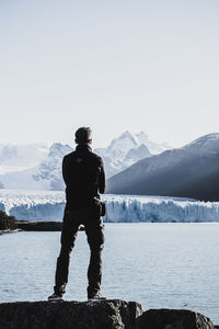 Man standing on snowcapped mountain against sky