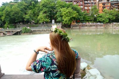 Woman sitting by lake against trees