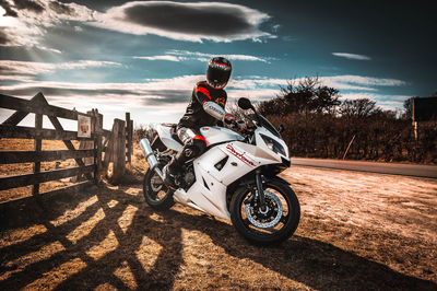 Man riding motorcycle on road against sky