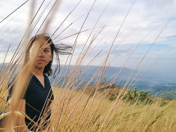 Woman looking away while standing by plants against sky